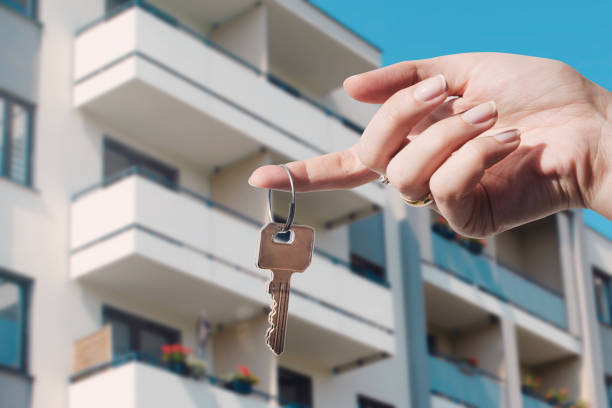 Hand holding a key in front of an apartment building, symbolizing setting up a real estate company in Dubai.