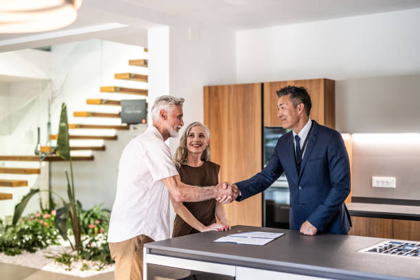 A couple shakes hands with a realtor in a modern office setting, symbolizing a real estate transaction in Dubai.